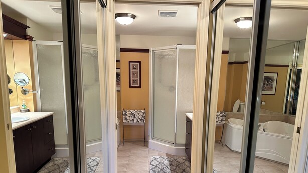 A modern bathroom with a shower, toilet, and bathtub, featuring a wooden floor and a patterned rug. - Le Littoral (Magog)