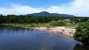 A lakeside beach with picnic tables and a gazebo. - Le Littoral (Magog)