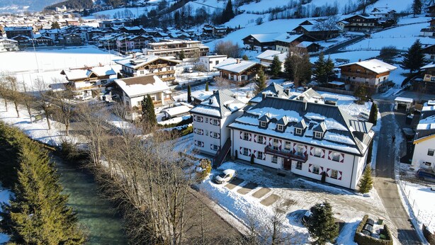 A snow-covered village with traditional buildings, a river, and mountains in the background. - Kitz Residenz Twelve Kaprun (Kaprun)