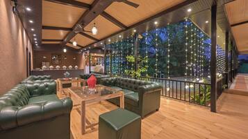 A modern lounge area with leather sofas, a glass coffee table, and a view of the outdoors.