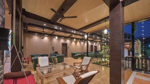 A spacious lounge area with wooden flooring, green sofas, and a glass table. - Khandala Valley Retreat (Mawal)