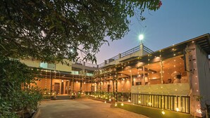 A courtyard with a covered seating area, a staircase, and a building with string lights. - Khandala Valley Retreat (Mawal)