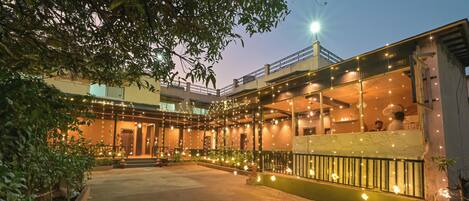 A courtyard with a covered seating area, a staircase, and a building with string lights.