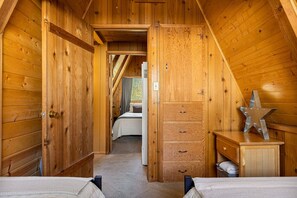 Een houten chalet van binnen met een slaapkamer, een badkamer en een gang.