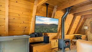 Une chaleureuse cabane en bois équipée d’une télévision, d’une cheminée et d’un canapé.