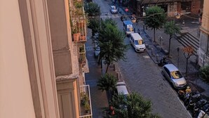 A street view with buildings, parked cars, and a clear sky. - La Maison di Partenope (Naples)