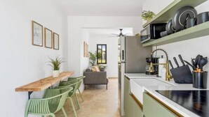 A modern kitchen with a dining area, green chairs, and a sofa.