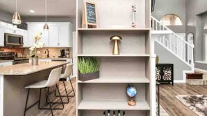 A modern kitchen with a central island, white cabinetry, and a 'FAMILY' sign on the upper shelf. - Beautiful 3-bedroom Patio Home in Houston w/ WiFi, AC near Champions Golf course (Houston)