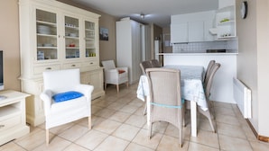 A compact living space with a dining area, kitchenette, and a white cabinet with glass doors. - Spacious Apartment With View (Middelkerke)
