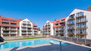 A modern hotel with multiple balconies, a swimming pool, and a well-maintained lawn. - Spacious Apartment With View (Middelkerke)
