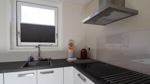 A modern kitchen with a window, stainless steel sink, and a built-in range hood. - Chalet in Friesland Near Large Lakes (Sint Nicolaasga)