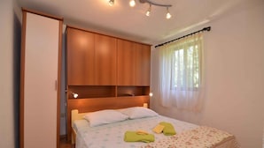 Quarto com cama, guarda-roupa de madeira e janela com cortinas.