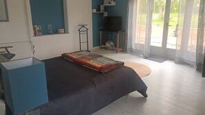 Een slaapkamer met een bed, een televisie, een ventilator en uitzicht op de omgeving.