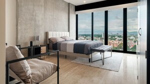 A modern bedroom with a large bed, a bedside table, a chair, and a view of a cityscape through large windows.