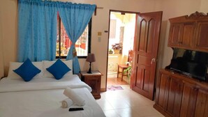 Habitación de hotel con cama, televisor, armarios de madera y una puerta que da a un balcón.