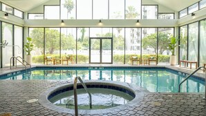 An indoor swimming pool with a hot tub, surrounded by large windows and outdoor views. - Lakeview apt 2 suítes 6 min Universal Studios free parking resort no extra fee (Orlando)
