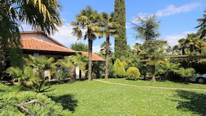 A house with a tiled roof, surrounded by a well-maintained garden with various trees and a lawn. - Bungalow mit Schönem Garten und Klimaanlage (Porec)