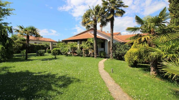 A house with a tiled roof, surrounded by lush greenery and a well-maintained lawn. - Bungalow mit Schönem Garten und Klimaanlage (Porec)