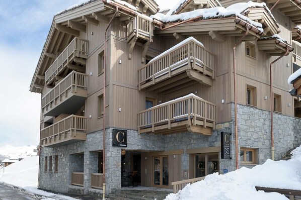 A multi-story hotel with balconies, stone facade, and a sign with a 'C' logo.