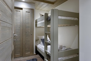 A bunk bed room with a wooden door and a small rug on the floor.
