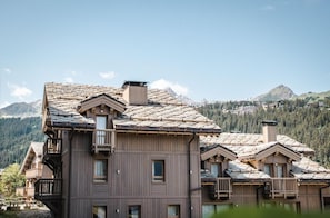 A multi-story wooden building with balconies and a mountainous backdrop.