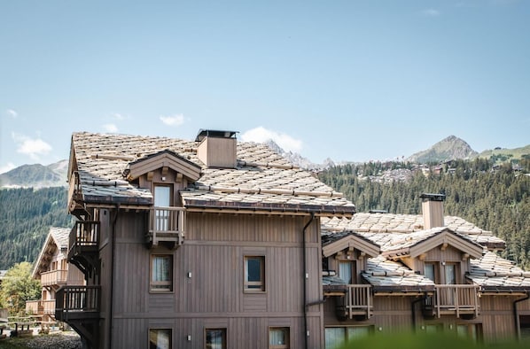 A multi-story wooden building with balconies and a mountainous backdrop.