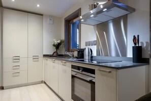 Une cuisine moderne équipée d’une hotte en acier inoxydable, d’une machine à café et d’un bloc à couteaux posé sur le plan de travail.