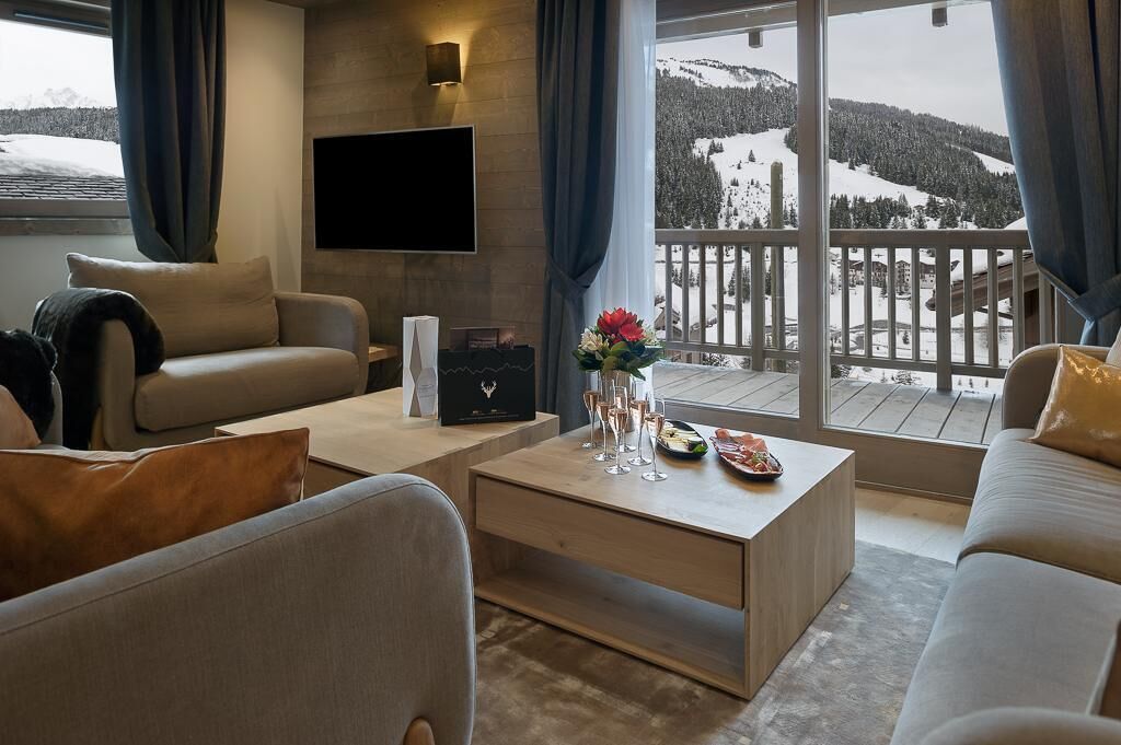 Un salon moderne avec un canapé, une table basse sur laquelle sont posées des boissons et un téléviseur fixé au mur.