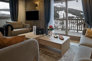A modern living room with a sofa, a coffee table with drinks, and a TV mounted on the wall.