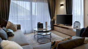 Ett modernt vardagsrum med en soffa, ett soffbord, en platt-TV och en dekorativ fågelbur.