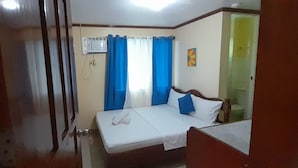 Une chambre à coucher comprenant un lit, une table de chevet, une fenêtre avec des rideaux et un appareil de climatisation.