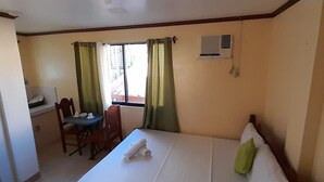 Une chambre d’hôtel avec un lit, un bureau, une chaise et une fenêtre avec des rideaux.