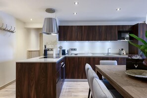 A modern kitchen with wooden cabinetry, a central island, and a dining area with a wooden table and chairs.