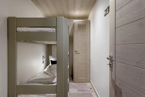 A compact bedroom with a bunk bed, a wooden door, and a small closet.