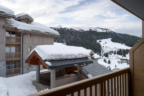 A snow-covered building with a balcony overlooking a mountainous landscape.