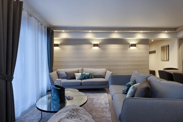 A modern living room with a grey sofa, a glass coffee table, and a fur rug.