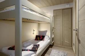 A bunk bed room with a wooden door and a small rug on the floor.