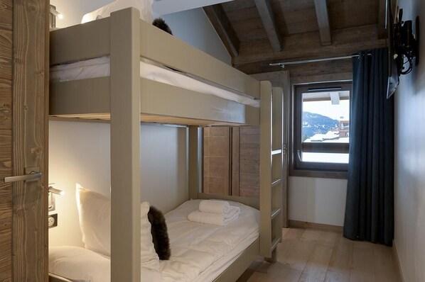 Une chambre avec des lits superposés offrant une vue sur un paysage montagneux par la fenêtre.