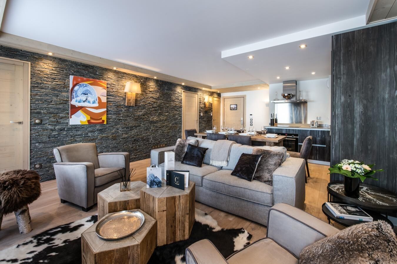 A modern living room with a stone wall, a dining area, and a kitchen.