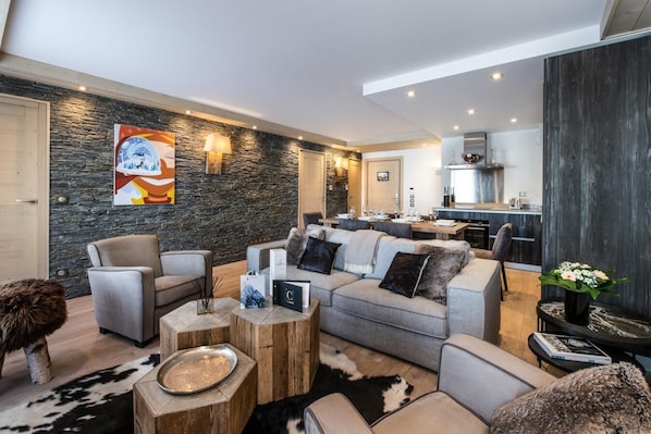 A modern living room with a stone wall, a dining area, and a kitchen.