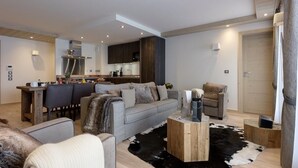 Ett modernt vardagsrum med en grå soffa, ett soffbord och en matplats med stolar.