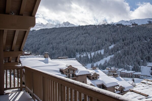 A snow-covered mountain landscape with a wooden balcony overlooking a village.