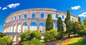 An ancient amphitheater with multiple arches and a surrounding garden. - Apartments in Pula/istrien 11169 (Pula)
