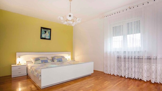 A bedroom with a bed, nightstands, a chandelier, and a window with curtains. - Apartments in Rovinj/istrien 11491 (Rovinj)