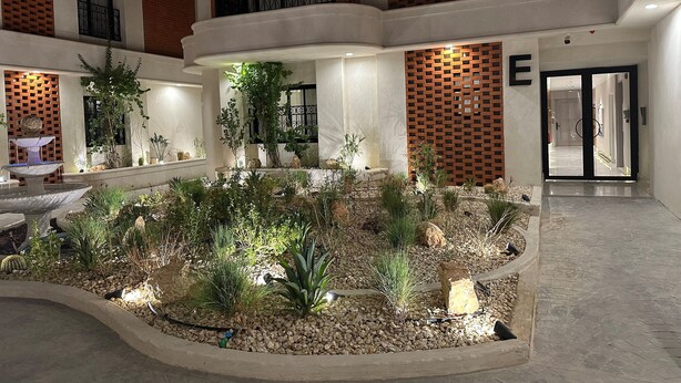 Un amplio atrio con jardín central, múltiples balcones y un diseño arquitectónico moderno.