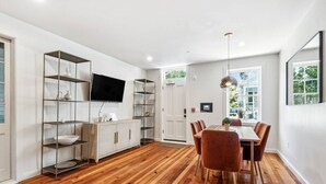 A modern dining area with a wooden floor, white walls, and a dining table with chairs.