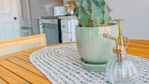 A cactus in a decorative pot on a wooden table with a woven placemat, set in a kitchen with white cabinets and stainless steel appliances. - Stay Near Gulfstream, Outlets & Airport (Pooler)