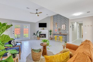 A spacious living area with a fireplace, seating, and a kitchen area in the background.