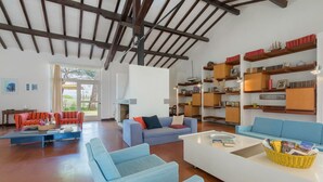 Een ruime woonkamer met een hoge nok, inbouwboekenplanken en een open haard.