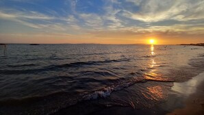 Een strand bij zonsondergang met rustige golven en een heldere lucht.